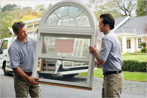 Two workers move a window for installation 